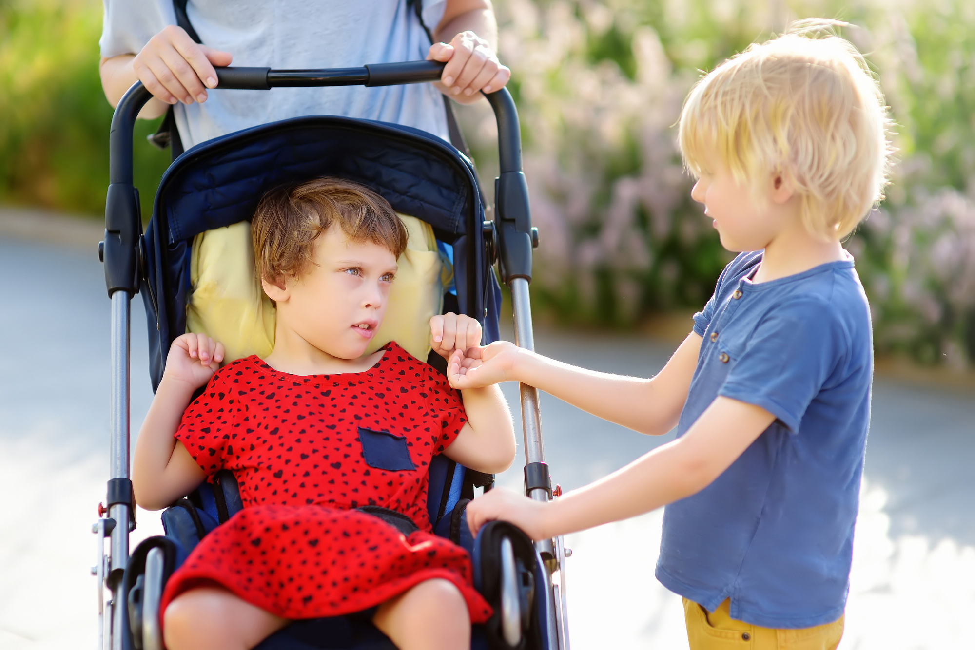 A woman with a boy and a disabled girl in a wheelchair walking i